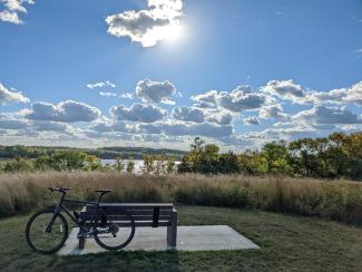 bike by a bench with clouds and nature in the background